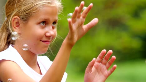 Niña-jugando-con-pompas-de-jabón-al-aire-libre.-Cámara-lenta.