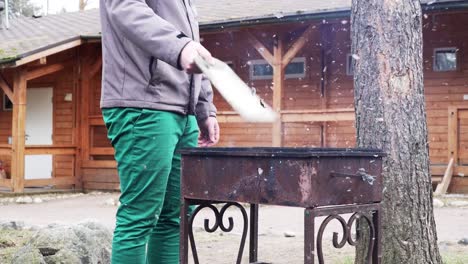 man-waves-a-board-over-burning-coals-in-the-grill