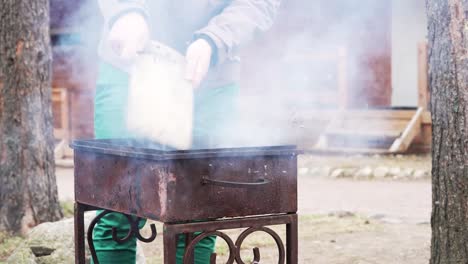 Mann-\"Wellenlinien\"-ein-Brett-über-glühende-Kohlen-im-grill