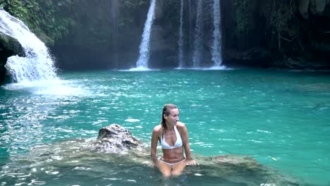 Young-woman-contemplating-a-beautiful-waterfall-on-the-Cebu-Island-in-the-Philippines.-People-travel-nature-loving-concept.-One-person-only-enjoying-outdoors-and-tranquillity-in-a-peaceful-environment