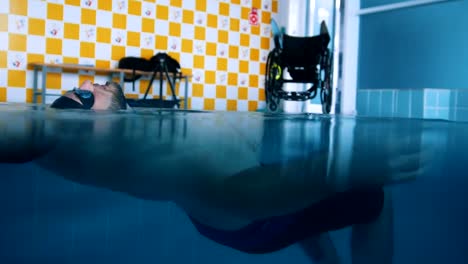 Disabled-man-lying-on-the-water-on-the-back-in-a-swimming-pool.-Underwater-shot