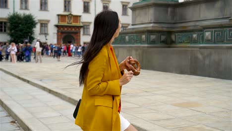 Hermosa-joven-sosteniendo-pretzel-y-relajante-en-el-Parque