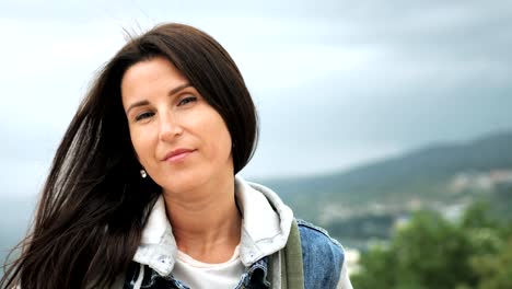 Slow-motion-portrait-of-hipster-female-tourist-standing-on-peak-of-mountain