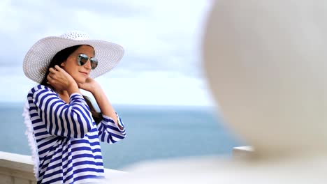 Seite-Ansicht-elegante-Frau-in-Hut-und-Sonnenbrille-bewundern,-Meer-und-Himmel-auf-Balkon-oder-Terrasse