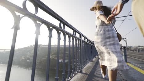 Woman-holding-man's-hand-and-showing-by-finger-on-bridge