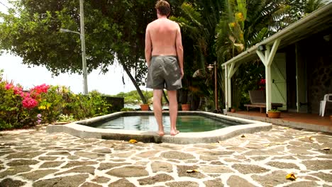 Hombre-salto-en-piscina-en-una-isla-tropical