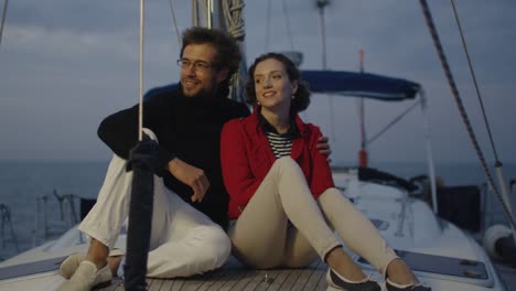 Young-couple-relaxing-on-a-yacht-in-the-sea-in-the-evening-at-sunset.