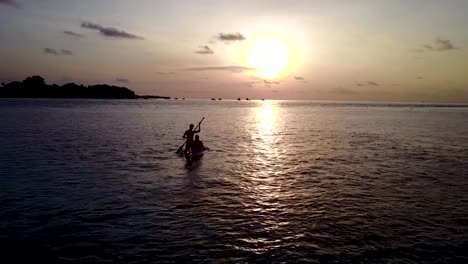 v04098-Aerial-flying-drone-view-of-Maldives-white-sandy-beach-2-people-young-couple-man-woman-paddleboard-rowing-sunset-sunrise-on-sunny-tropical-paradise-island-with-aqua-blue-sky-sea-water-ocean-4k