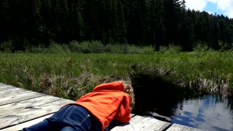 Girl-Leaning-Over-a-Wooden-Pier-at-a-Cottage