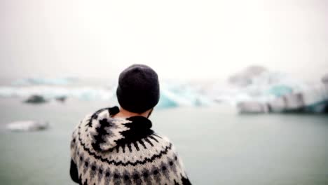 Joven-barbudo-a-hombre-de-pie-en-la-laguna-de-hielo-Jokulsalon-y-buscando-en-los-glaciares,-naturaleza-del-norte-de-Islandia