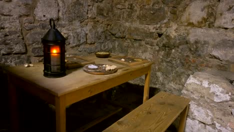 Wooden-table-in-a-stone-house-with-a-lamp-and-food