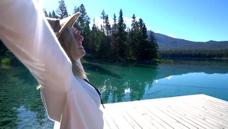 Woman-arms-outreached-by-alpine-lake-in-the-Canadians-rockies