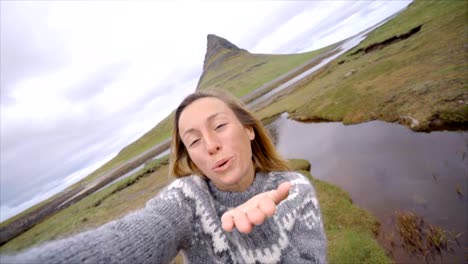 Slow-motion-Selfie-portrait-of-tourist-female-blowing-kiss-in-Iceland-at-Kirkjufell-mountain