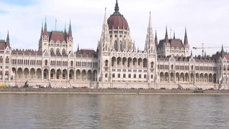 El-paisaje-del-edificio-del-Parlamento-húngaro-con-consejos-de-la-nave-en-el-Danubio-en-Budapest,-Hungría-en-la-tarde.