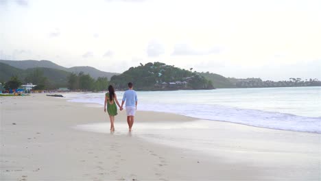 Young-couple-on-white-beach-during-summer-vacation.-Happy-family-enjoy-their-honeymoon