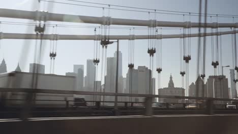 A-view-of-Lower-Manhattan-skyline-filmed-in-the-afternoon-from-the-Uber-taxi-car-driving-on-the-eastern-part-of-the-bridge-above-the-East-River-in-New-York,-United-States