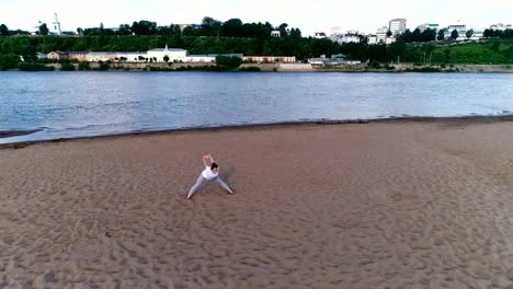 Woman-doing-yoga-on-the-beach-by-the-river-in-the-city.-Beautiful-view.