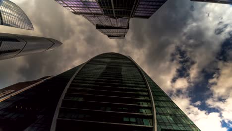 Bottom-up-Blick-auf-rotierende-Wolkenkratzer-und-fliegenden-Wolken,-Zeitraffer,-hyper-Zeitraffer