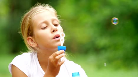 Little-girl-playing-with-soap-bubbles-outdoor.-Slow-motion.