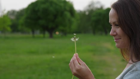 Frau,-die-auf-kleinen-Samen-auf-Löwenzahn-Kopf