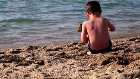 Niño-en-una-playa-de-mar-jugando-en-la-arena