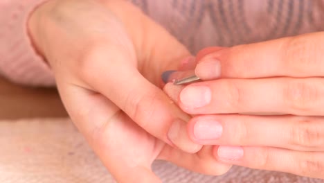 Frau-entfernt-Schellack-aus-Nagel-mit-Drücker.-Close-up-Hand.