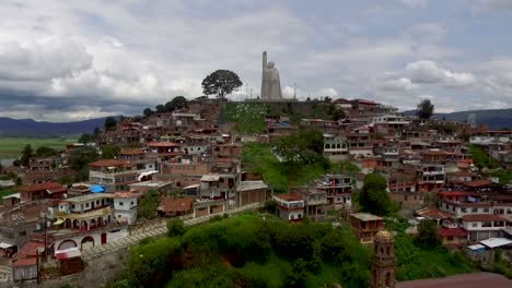 Drone-approaching-the-iconic-statue-on-top-of-the-island-of-Janizitio,-Mexico