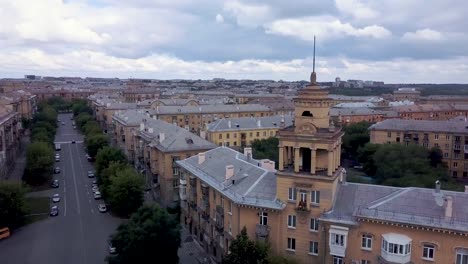 Drone-en-vuelo-cerca-de-la-torre-de-estilo-antiguo-con-fábrica-en-el-fondo