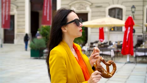 Hermosa-joven-sosteniendo-pretzel-y-relajante-en-el-Parque