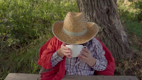 Una-mujer-en-un-sombrero-de-paja-tomando-té