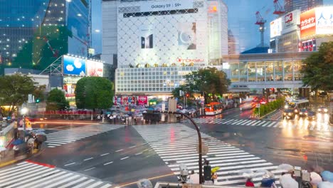 Shibuya-district-at-rainy-day-with-crowd-passing-crosswalk.-Tokyo,-Japan.-view-through-window.-4K-Timelapse.