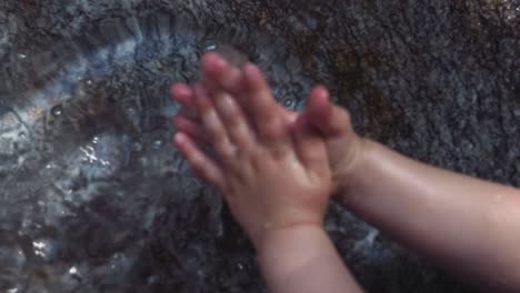 Mano-del-niño-en-Cuenca-de-la-fuente-de-agua