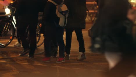 City-atmosphere-at-night---people-crossing-street,-low-angle-shot-of-feet-and-legs-walking-in-the-street-in-the-evening