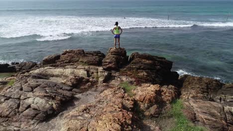 Young-woman-open-arms-on-cliff-edge-at-seaside,aerial-drone-4k-footage