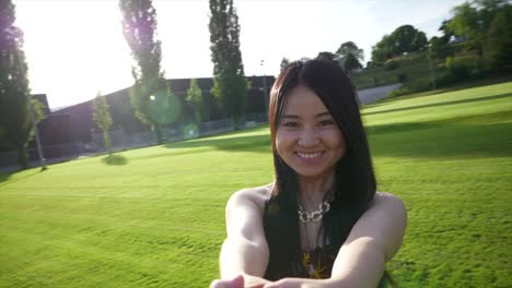 Happy-young-woman-holding-hands-and-turning-around-on-grass-field