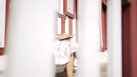 Woman-with-notebook-on-bench-near-building