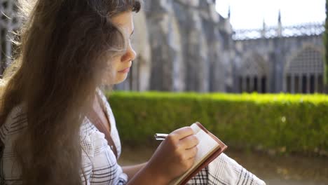 Woman-writing-in-notepad-in-monastery