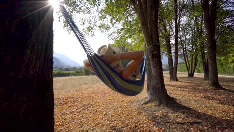 Mujer-joven-Serena-descanso-en-hamaca-a-disfrutar-de-la-naturaleza-puesta-de-sol-en-verano-tardío.-Gente-de-viaje-disfrutando-de-libertad-y-ambiente-tranquilo---cámara-lenta