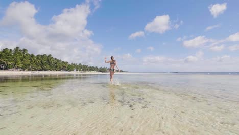 Fröhliche-junge-Frau-im-Badeanzug-auf-Meerwasser-am-Sommerstrand