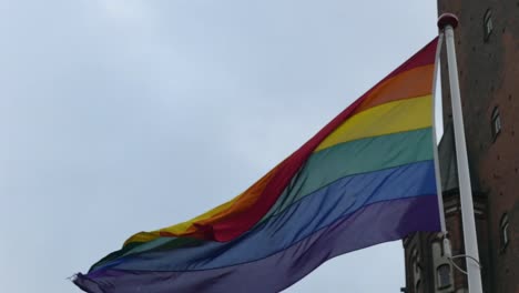 Bandera-de-arco-iris-en-el-centro-de-la-ciudad.-Bandera-arcoíris-(movimiento-LGBT)-revoloteando-en-el-viento.-De-cerca.