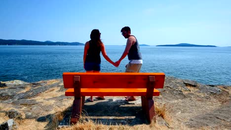 Frau-führt-Mann-auf-Park-Bench-mit-Blick-auf-das-Wasser