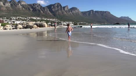 Junge-läuft-in-Richtung-der-Kamera-am-Strand,-Südafrika