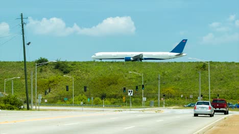 Cars-Driving-Next-to-Airport-with-Passing-Airliner