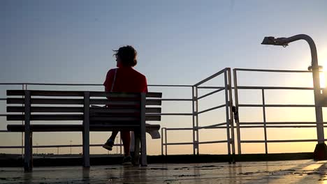 Silhouette-of-a-senior-woman-sitting-on-a-cruise-ship-yacht-deck-at-sunset