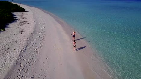 v03813-Aerial-flying-drone-view-of-Maldives-white-sandy-beach-on-sunny-tropical-paradise-island-with-aqua-blue-sky-sea-water-ocean-4k-2-people-young-couple-man-woman-playing-ball-fun-together