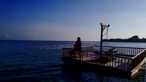 v03832-vuelo-drone-vista-aérea-de-Maldivas-playa-2-personas-pareja-hombre-mujer-relajante-en-la-isla-de-paraíso-tropical-soleado-con-cielo-azul-aqua-agua-mar-4k-flotante-pontoon-embarcadero-el-sol-juntos