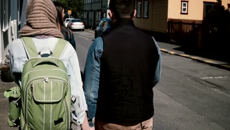 Back-view-of-young-tourists-couple-walking-through-the-street-in-bright-sunny-day.-Man-and-woman-on-a-romantic-date