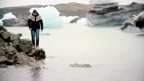 Young-handsome-man-standing-on-the-shore-in-Jokulsalon-ice-lagoon-and-looking-on-glaciers-in-Iceland