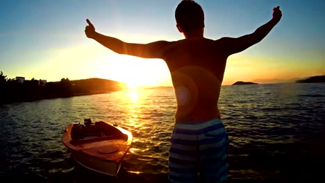 WINNING-CONCEPT,-Crane-shoot-of-winner-positive-man-raising-hands-toward-ocean-sunset