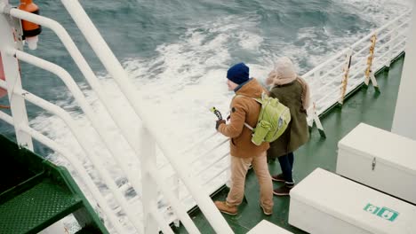 Draufsicht-des-jungen-Paares-stehen-an-Bord-des-Schiffes.-Mann-und-Frau-mit-Action-Kamera-genießen-den-Blick-auf-Meer